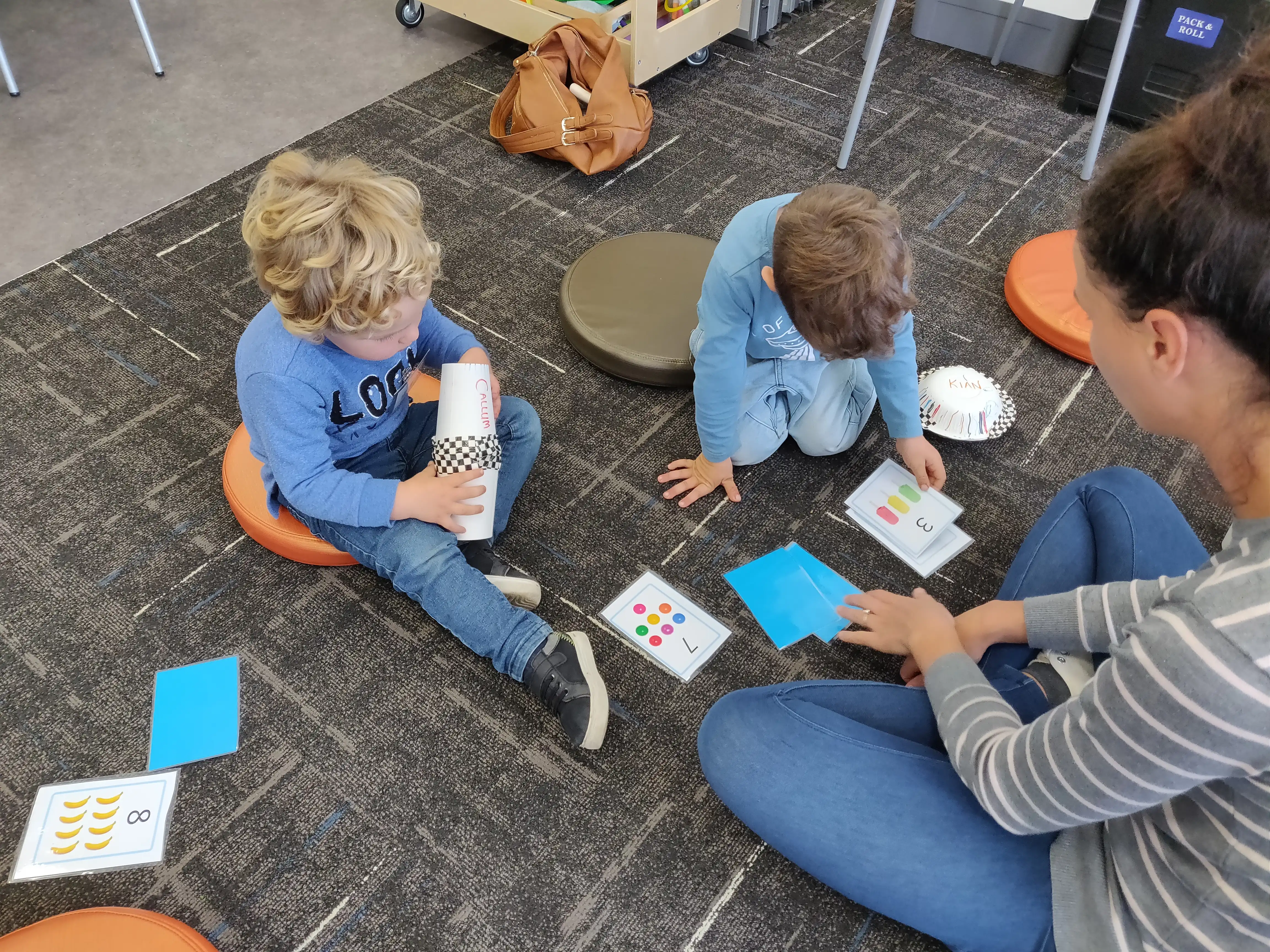 Children with mother counting on floor. 